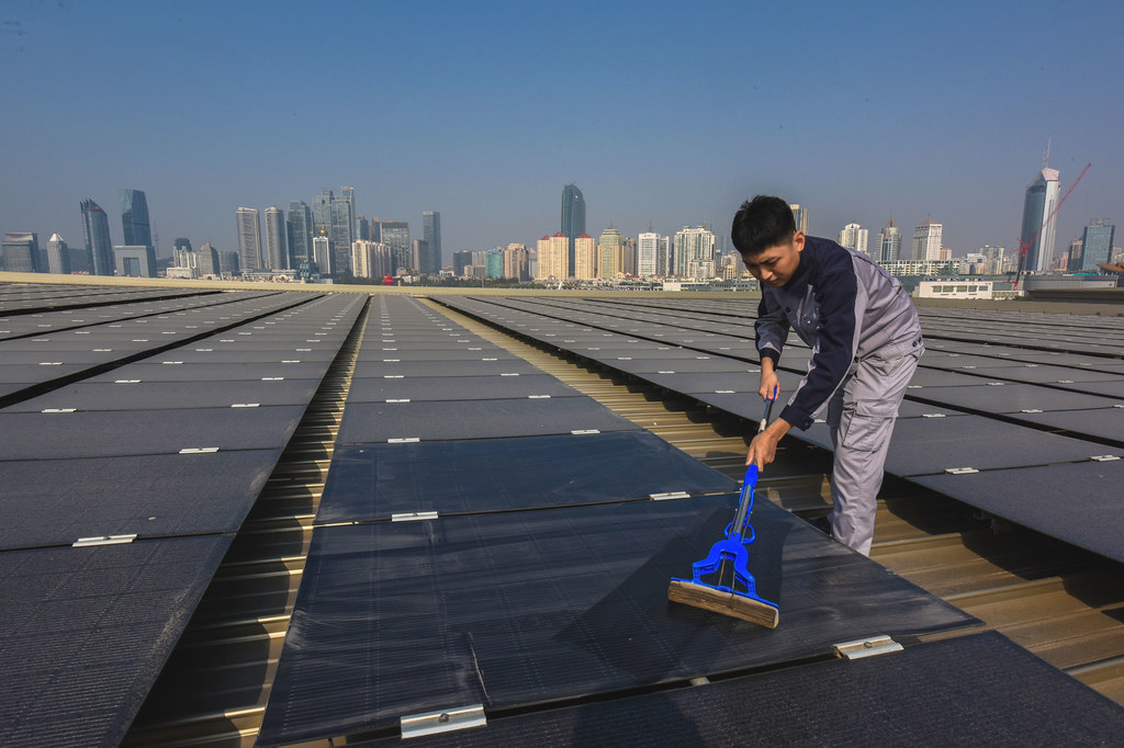 Un empleado mantiene limpias las instalaciones de una granja solar en China.
